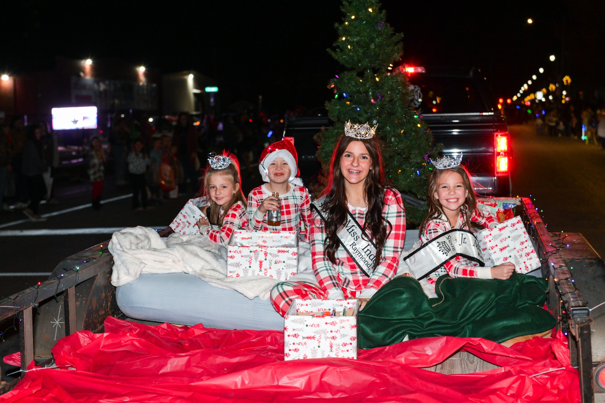 Kids riding with wrapped presents on a Christmas parade trailer