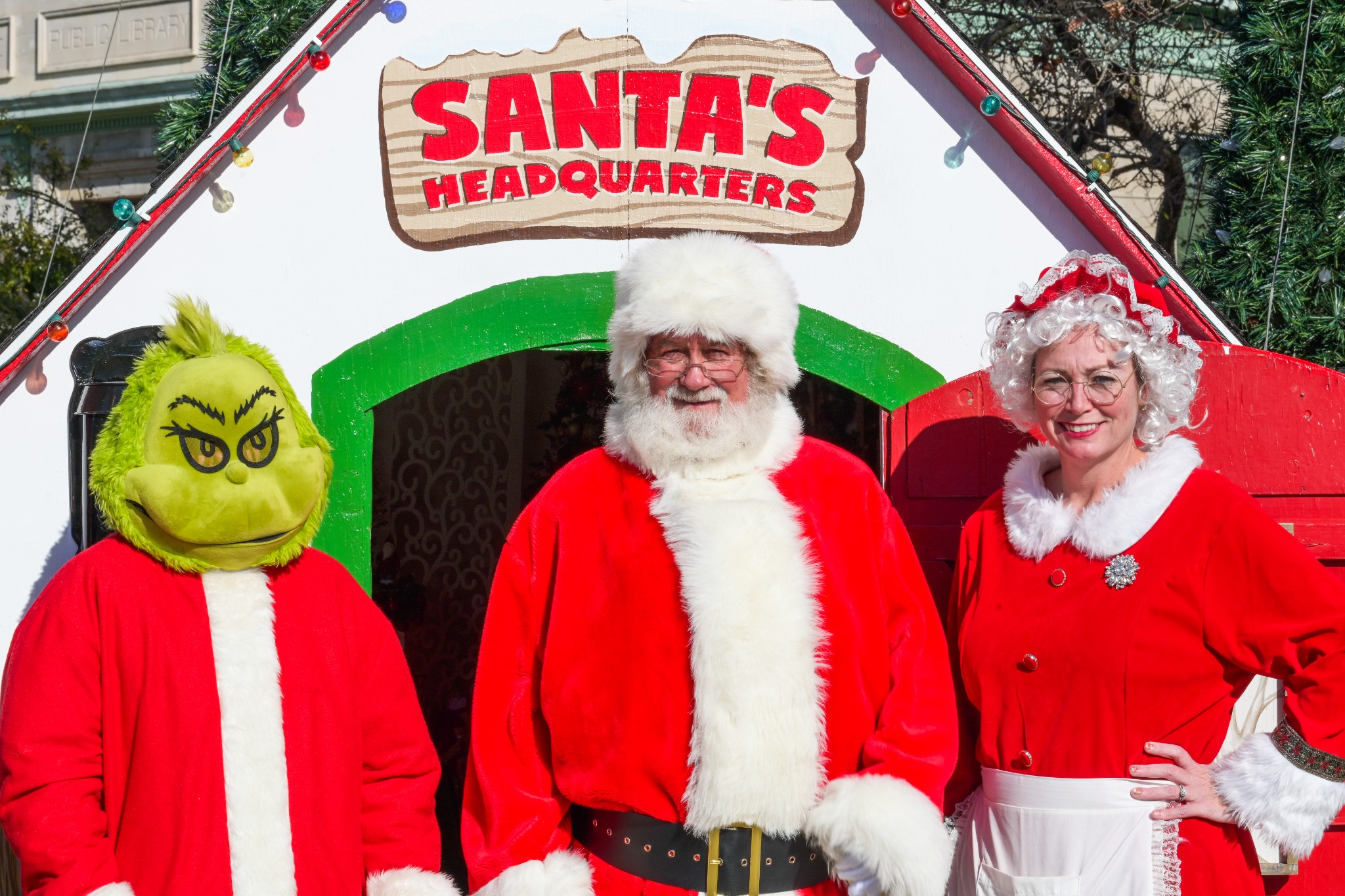 Santa, Mrs. Claus and the Grinch in front of Santa's Headquarters