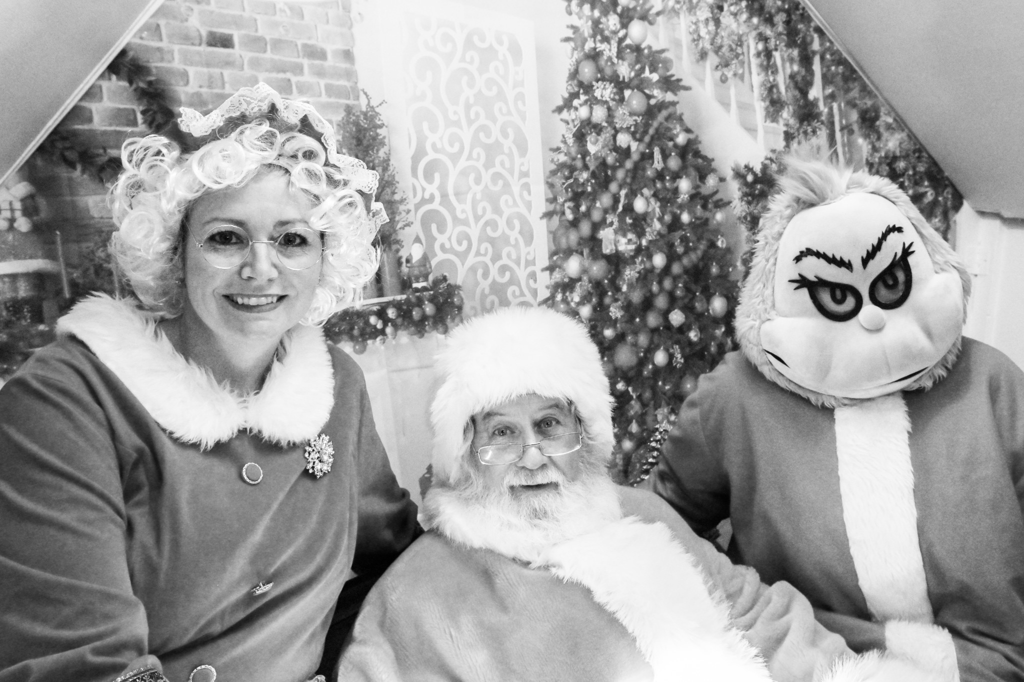 Black and white photo of Mrs. Claus, Santa and the Grinch inside the Santa House
